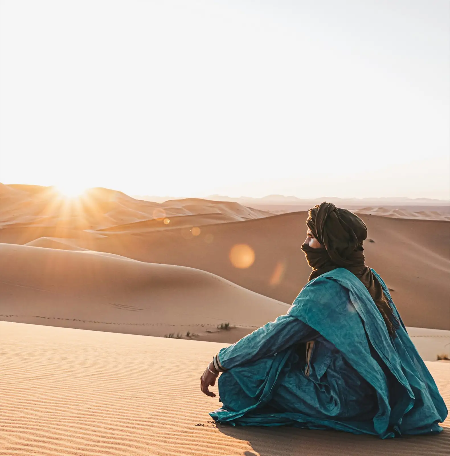 Viajera sentada en las dunas del Sahara al atardecer